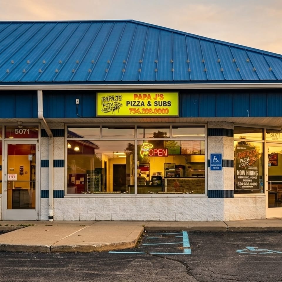 Exterior of Papa J's Pizza & Subs with a blue roof and yellow sign at sunset.